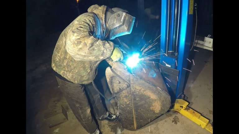 Welder performing arc welding on ship hull with protective gear and bright blue arc light